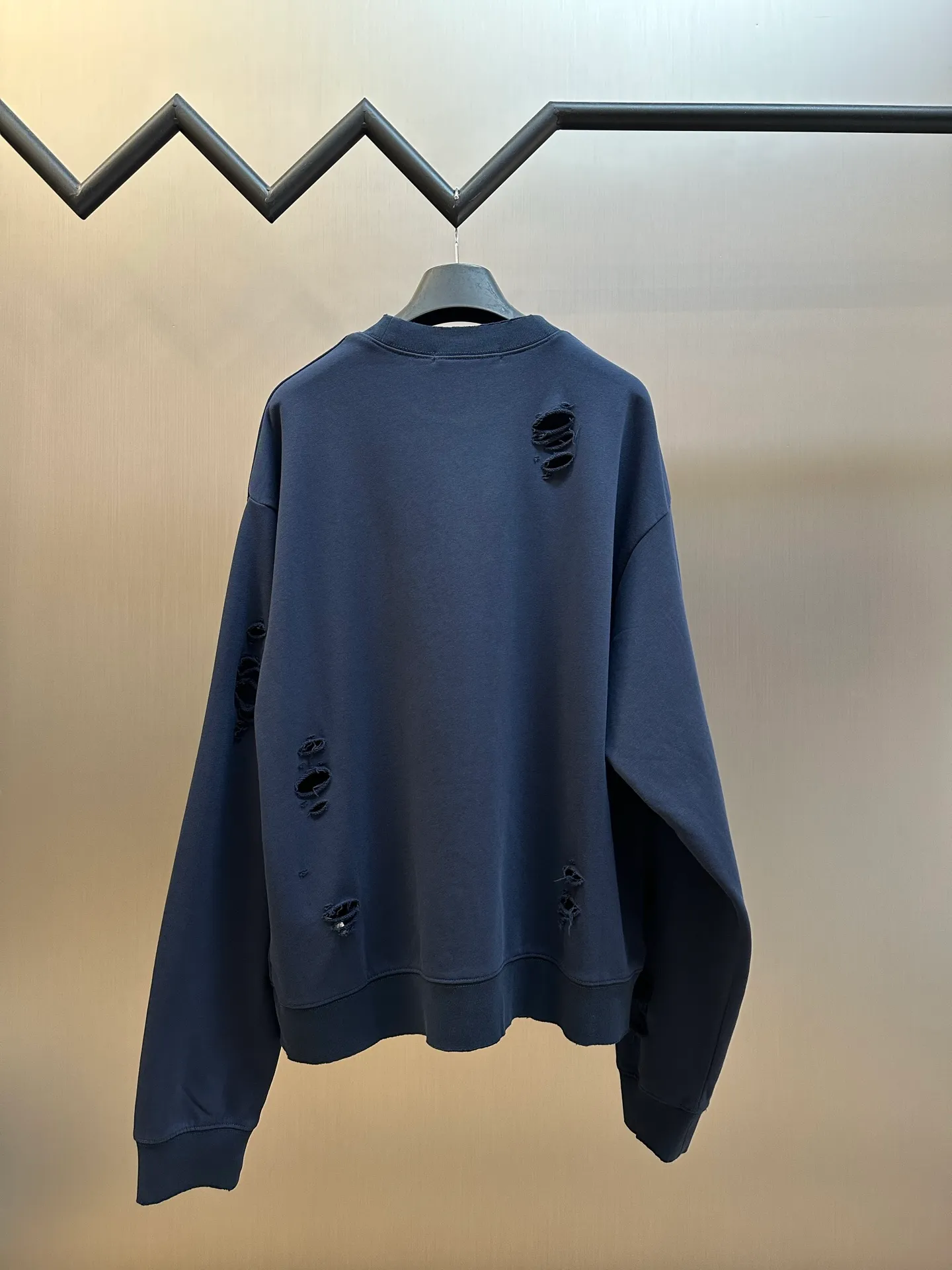 Ac Studios distressed logo sweatshirt Customized etched soft-extract raw cotton fleece, deep dark blue is quiet and restrained, matte fog base color, symbiotic with the destructive texture, Retro pioneer style, denim rivet style logo printing on the chest, replica of the old steel seal embossed texture, the color will naturally fade with the washing of the garment, and the whole body will be more Artificially torn holes are carefully arranged, and the raw edges of the rips are stretched out wantonly, replicating the wear and tear traces eroded by time, destroying and deconstructing the regular shackles of standard clothing, integrating decadent street aesthetics and Nordic minimalist design genes, creating a pioneering ready-to-wear product with outstanding character. Glue printing is used. The chest printing is modified by the film screen three times. The glue liquid paint is used to print the pattern on the fabric, and the fabric is baked to fix the printed pattern. Many parts of the body of the garment are worn and worn at regular intervals, with manual brush marks added to add texture and depth to the surface of the garment to imitate the texture of natural wear and tear size: s m l xl